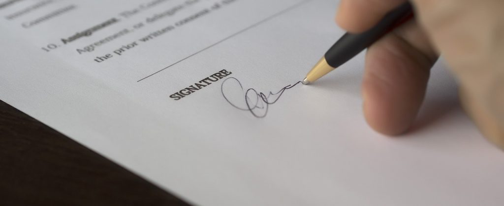 A hand signing a document